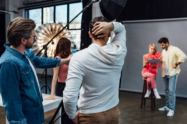 Visão traseira do homem tocando o cabelo enquanto estava perto do diretor de arte — Fotografia de Stock