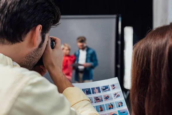 Back view of photographer taking photo of model and art director in photo studio — Stock Photo