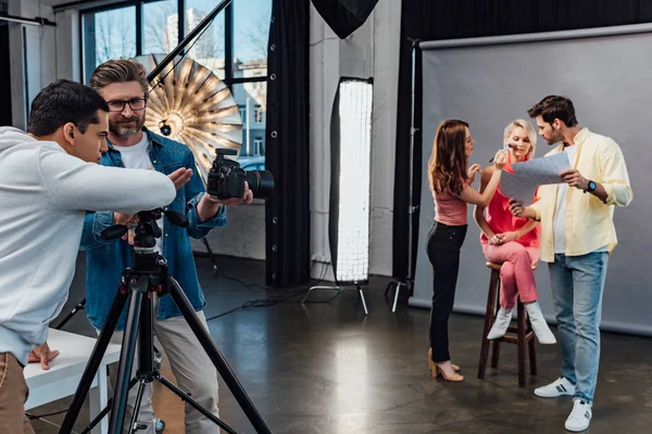 Foco seletivo do fotógrafo olhando para a câmera digital perto de diretor criativo barbudo — Fotografia de Stock