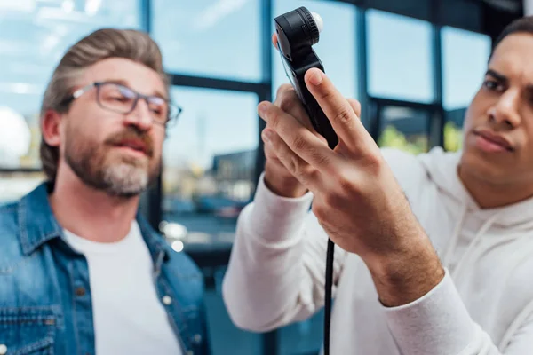 Selective focus of photographer holding light meter near art director — Stock Photo