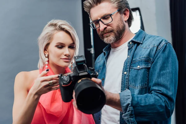 Bonito arte diretor segurando câmera digital perto atraente modelo — Fotografia de Stock