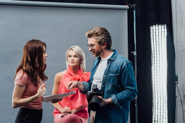 Attractive art director looking at photographer near beautiful model — Stock Photo