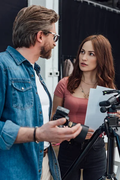 Foco seletivo de diretor criativo atraente olhando para fotógrafo barbudo em óculos — Stock Photo