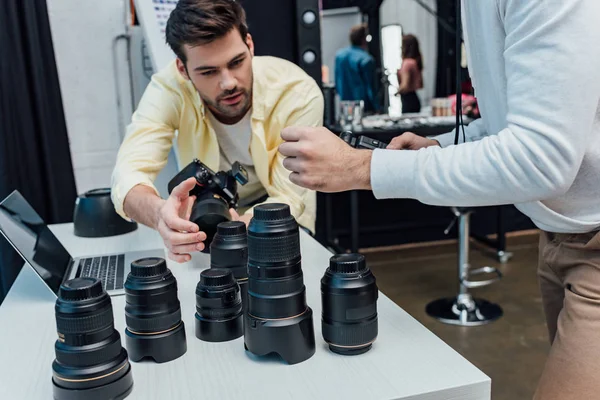 Vista recortada do diretor de arte em pé perto de fotógrafo e lentes de foto — Fotografia de Stock