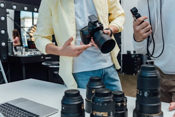 Foco seletivo de diretor de arte em pé com fotógrafo perto de lentes de foto — Fotografia de Stock