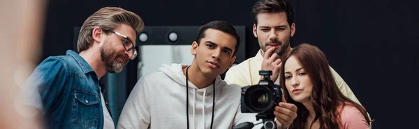 Colpo panoramico di direttore artistico felice vicino a colleghi e macchina fotografica digitale in studio fotografico — Foto stock