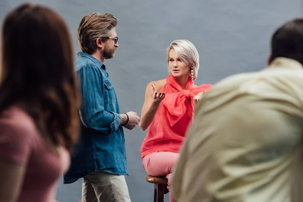 Selective focus of model gesturing near bearded creative director in photo studio — Stock Photo