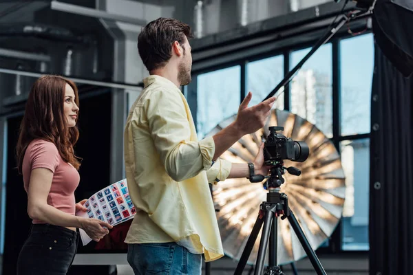 Diretor de arte atraente segurando colagem de fotos e olhando para o fotógrafo — Fotografia de Stock