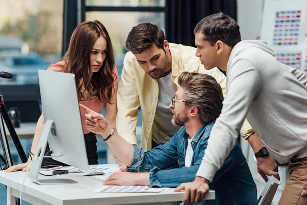 Diretor de arte bonito em óculos apontando com o dedo para monitor de computador — Stock Photo