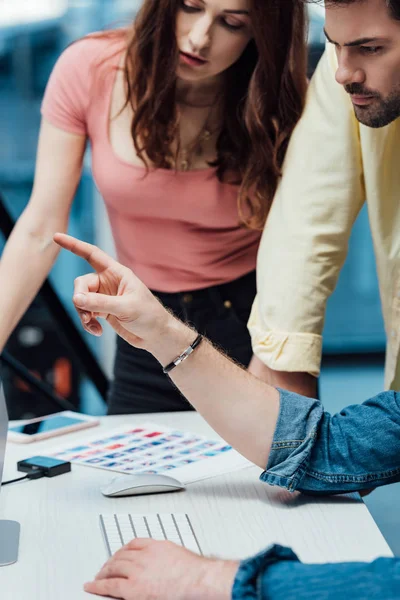 Cropped view of art director pointing with finger near coworkers — Stock Photo