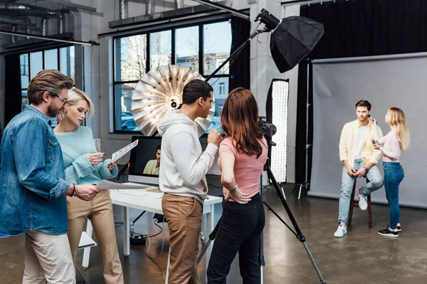 Backstage en estudio fotográfico moderno con modelo, director de arte y asistentes - foto de stock