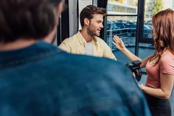 Selective focus of attractive photographer gesturing while looking at man near art director — Stock Photo