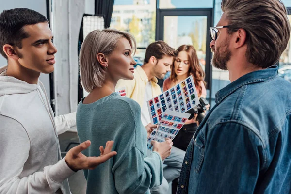 Selective focus of art director looking at assistant gesturing in photo studio — Stock Photo