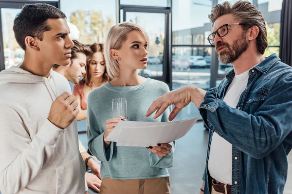 Foyer sélectif du directeur créatif dans les lunettes gesticulant près des collaborateurs — Photo de stock