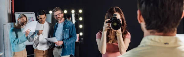 Tiro panorâmico de fotógrafo tirando foto de homem perto de diretor de arte e colegas de trabalho — Fotografia de Stock