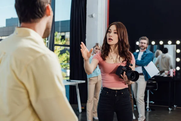 Foyer sélectif du photographe gesticuler et regarder le modèle près de ses collègues — Photo de stock