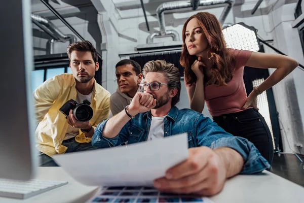 Enfoque selectivo del director creativo pensativo y asistentes en el estudio de fotografía — Stock Photo