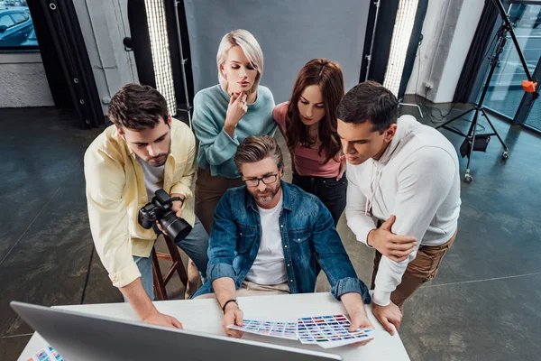 Vue aérienne du directeur créatif et des assistants regardant le moniteur d'ordinateur dans le studio photo — Photo de stock