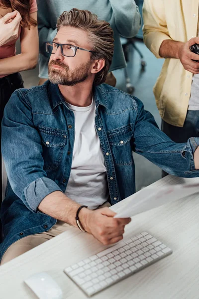 Cropped view of assistants standing near art director in glasses — Stock Photo