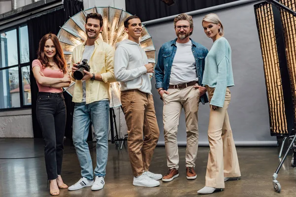 Equipo positivo sonriendo mientras mira a la cámara en el estudio de fotos - foto de stock