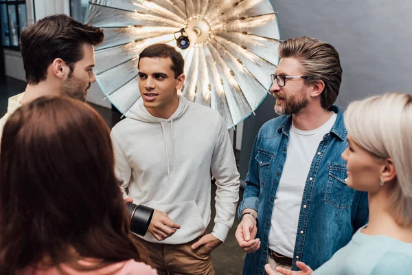 Selective focus of men speaking near women in photo studio — Stock Photo