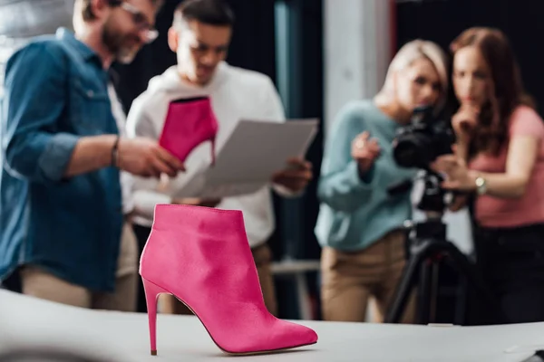 Foco seletivo sapato rosa perto da equipe no estúdio de fotografia — Fotografia de Stock