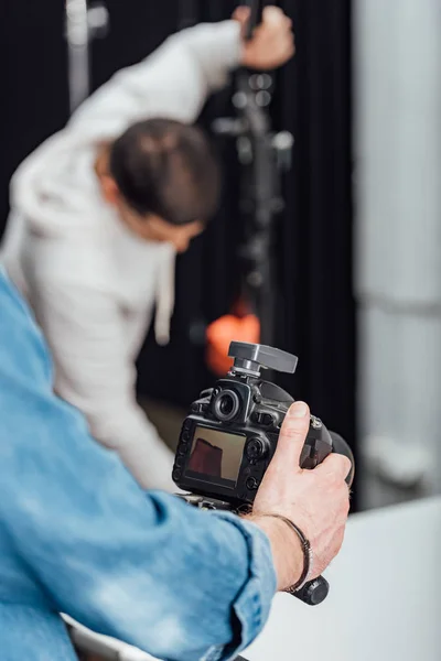 Enfoque selectivo de la cámara digital moderna en el trípode cerca del fotógrafo - foto de stock