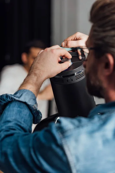 Selective focus of bearded man touching reflector photo studio — Stock Photo