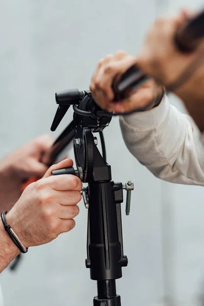 Vista ritagliata di uomini che tengono stand luce in studio fotografico — Foto stock