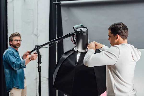 Selective focus of man touching reflector during photo shoot — Stock Photo