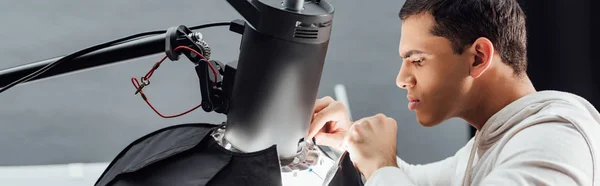 Prise de vue panoramique d'un bel homme regardant un réflecteur dans un studio photo — Photo de stock