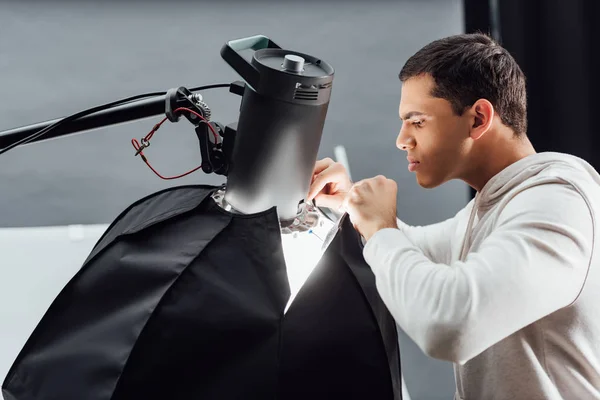 Side view of handsome man looking at reflector in photo studio — Stock Photo