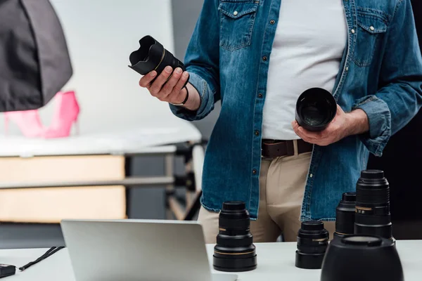 Vista ritagliata di uomo che tiene lenti della fotocamera in studio fotografico — Foto stock