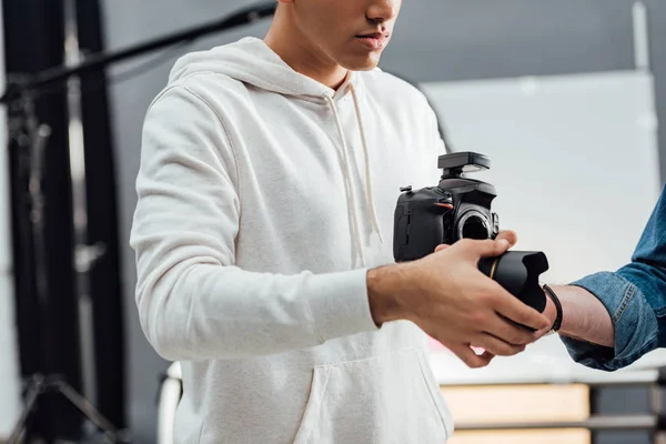 Visão recortada do fotógrafo segurando câmera digital e levando lente da câmera — Fotografia de Stock