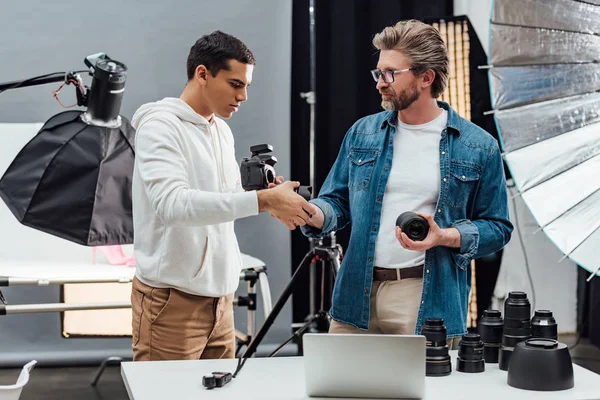 Handsome art director giving photo lens to photographer — Stock Photo