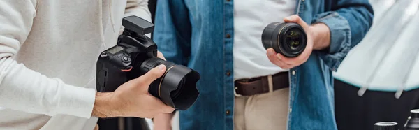Fotografía panorámica del director de arte sosteniendo lente fotográfica cerca del fotógrafo - foto de stock