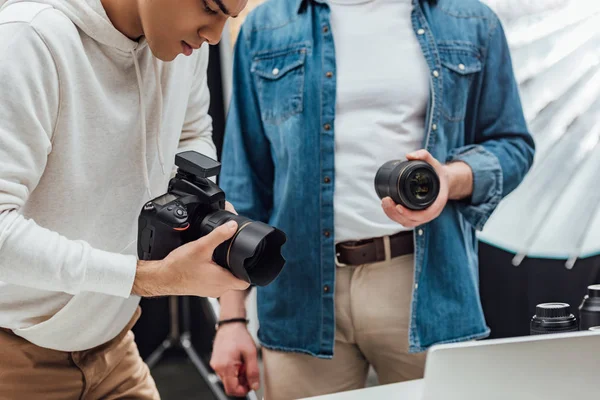 Vista recortada del director de arte sosteniendo lente de foto cerca del fotógrafo - foto de stock