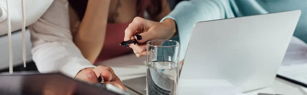 Panoramic shot of art director holding pen near clipboard and assistant — Stock Photo