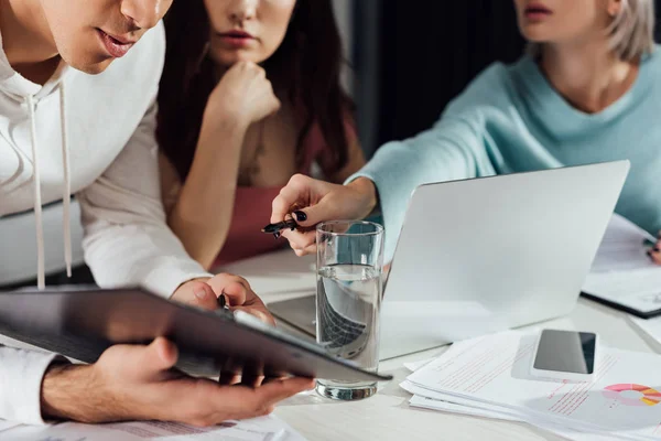 Vue recadrée du directeur artistique tenant un stylo près du presse-papiers et des assistants — Photo de stock