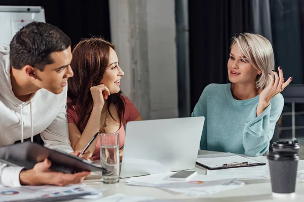 Selektiver Fokus glücklicher Art Director gestikuliert in der Nähe von Assistenten — Stockfoto