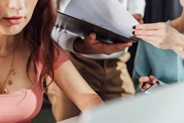 Abgeschnittene Ansicht eines Art Directors, der Dokumente in die Nähe von Assistenten nimmt — Stockfoto