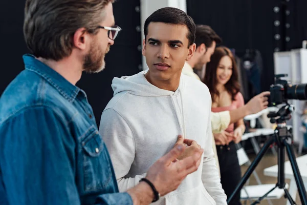 Selective focus of handsome assistant looking at art director in glasses — Stock Photo