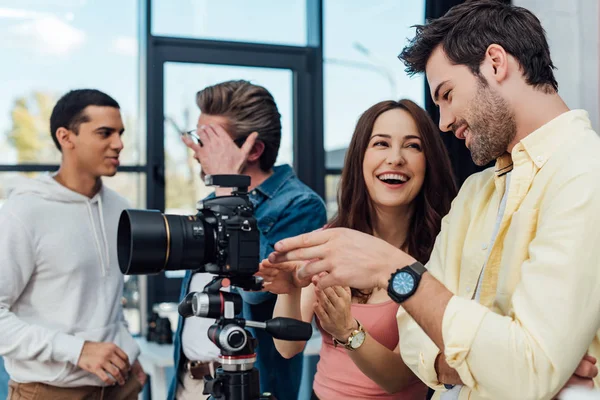 Selective focus of happy coworkers standing near digital camera — Stock Photo