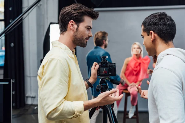 Selektiver Fokus des Fotografen gestikuliert nahe Assistent im Fotostudio — Stockfoto