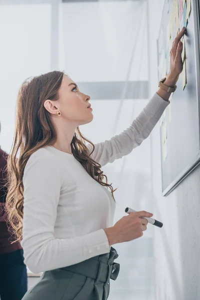 Seitenansicht des schönen Gedränges Master hält Marker Pen in der Nähe Bord — Stockfoto