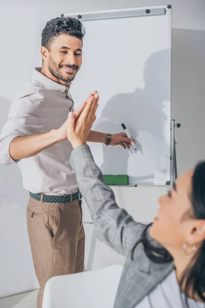 Enfoque selectivo de feliz mezcla raza scrum maestro dando alta cinco a asiático mujer de negocios - foto de stock