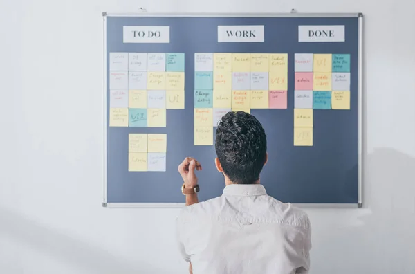 Vue arrière du scrum master debout près de la planche avec des notes collantes — Photo de stock