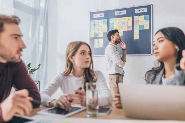 Selective focus of pensive mixed race man near coworkers — Stock Photo