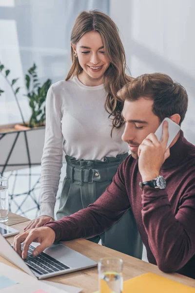 Enfoque selectivo de la mujer de negocios feliz mirando hombre de negocios hablando en el teléfono inteligente - foto de stock