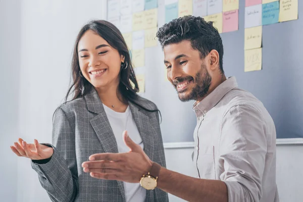 Alegre multicultural scrum mestres gesticulando enquanto sorrindo no escritório — Fotografia de Stock